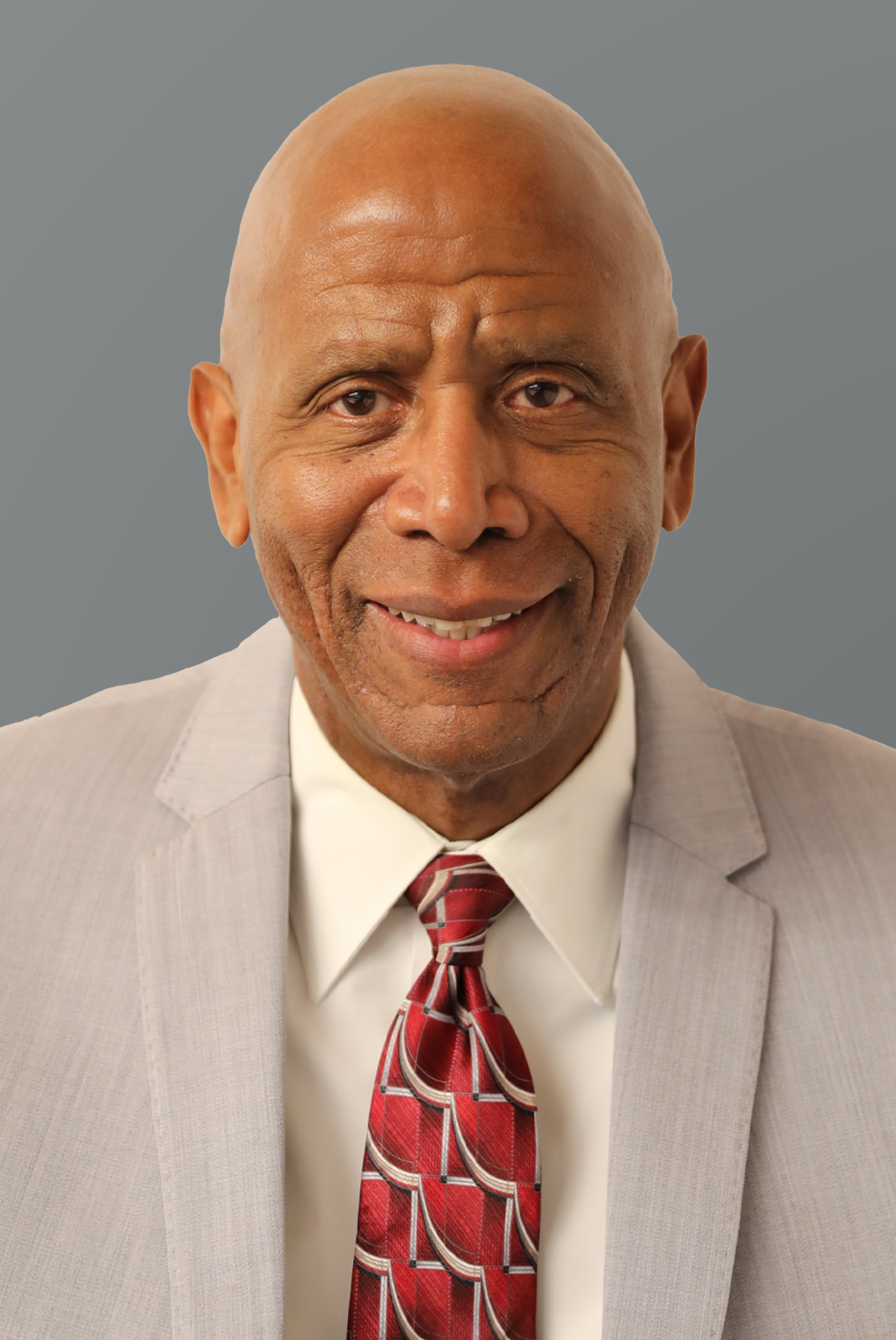 Headshot of Geoffrey Evans, a member of Interfor's Board of Directors, wearing a grey suit and red tie against a grey background.